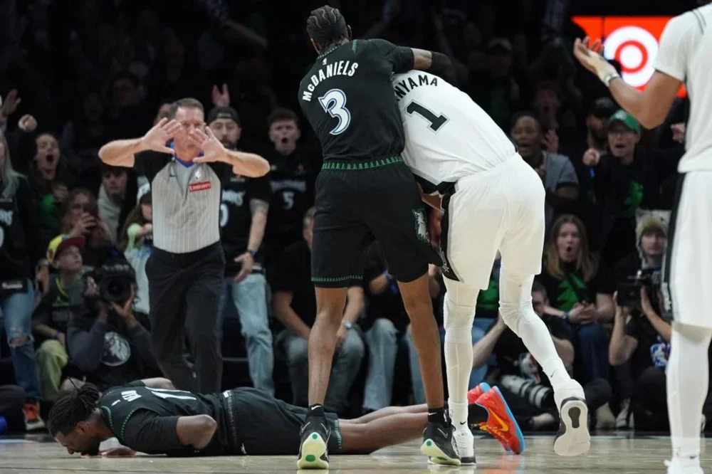 Naz Reid, en el suelo tras el codazo de Victor Wembanyama,sujetado por Jaden McDaniels.